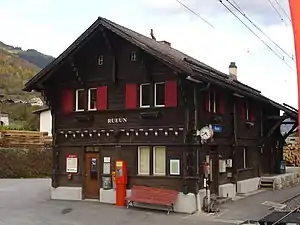 Two-story wooden building with gabled roof next to double-track railway line