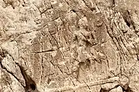 Sar-e Pol-e Zahab, relief I. Beardless warrior with axe, trampling a foe. Sundisk above. A name "Zaba(zuna), son of ..." can be read. This is possibly the son of Iddin-Sin, a ruler of the Kingdom of Simurrum.