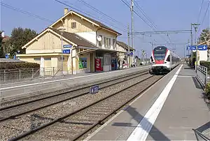 Two-story building with gabled roof and side platforms next to double-track railway line