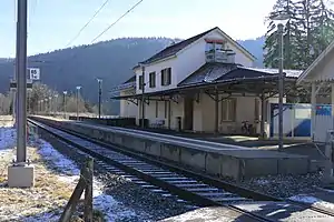 Two-story building with gabled roof next to single-track railway line