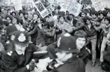 A confused scene as police pull away a protester, with other demonstrators close by