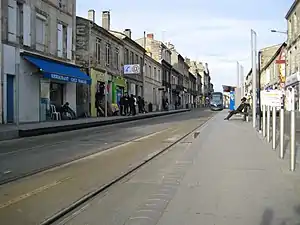 Double-track railway line in the street with side platforms flanked by two- and three-story buildings