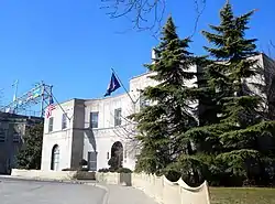 A two-story stone building with trees in front