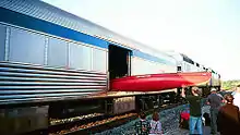 A man loading a canoe onto a baggage car, while a family watches