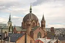 Large, fanciful building with towers, pointed arches, and a large dome in the center, topped by a spire.