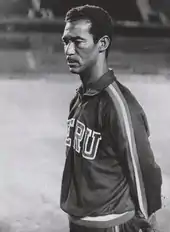 Photo of a man with a moustache, wearing a sports outfit, in a thoughtful pose