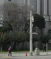 A square utility pole with an ornamental streetlight