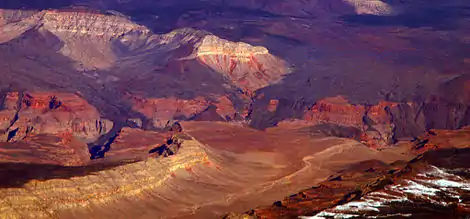 View showing hardened flows of dark volcanic rock descending over the side of a canyon