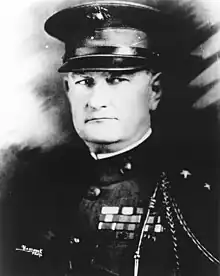 an image of a white male in his military uniform with a hat on. Military style ribbons are clearly visible.