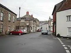 Street scene showing shops and houses with cars.