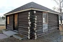 An angle of the building showing its corner, with a side visible and bare trees in the background